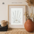 Framed artwork of sunrays and a golden cross, on a neutral wall, featuring 'Krista Bell's Studio' branding.