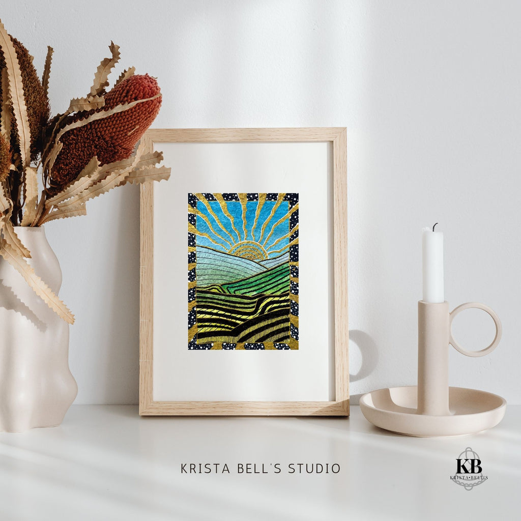 Framed artwork of a sun and landscape on a white surface with decorative items.