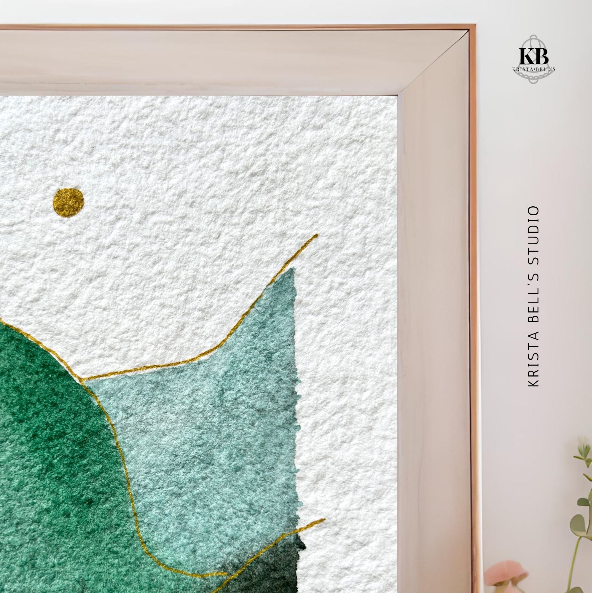 Framed artwork showing the upper corner of a watercolor landscape and 'KB' logo on a white background