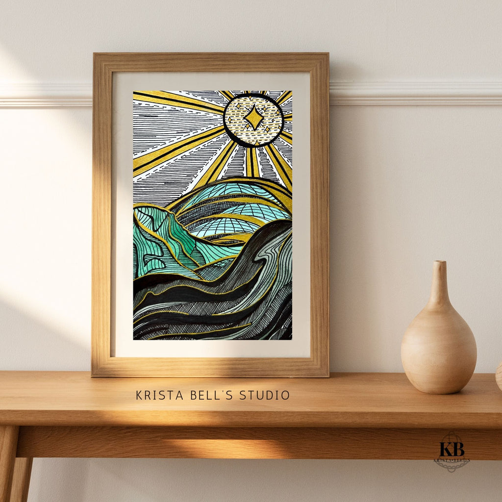 Framed artwork of a graphic landscape and golden rays, by Krista Bell's Studio on a wooden shelf with a neutral background