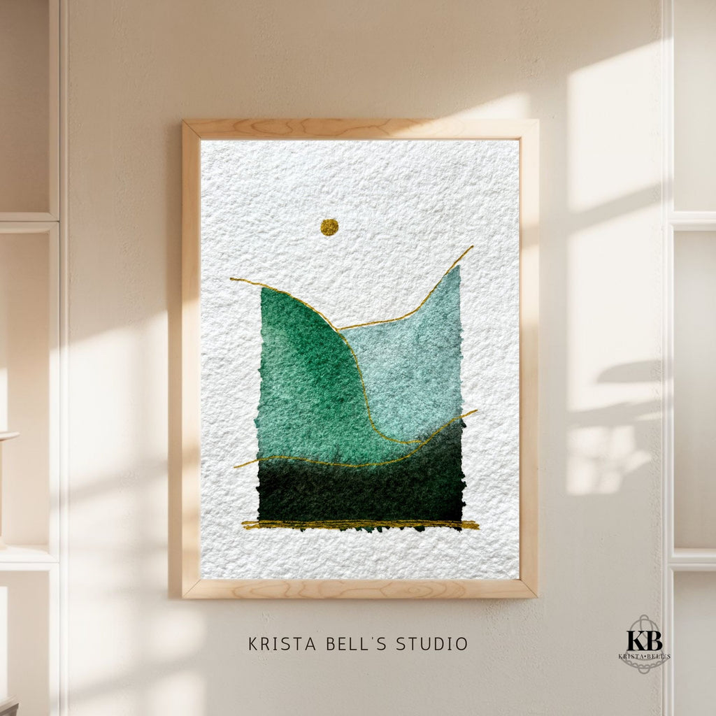 Framed watercolor landscape art piece with green and black shapes on a textured white background, displayed on a wall.