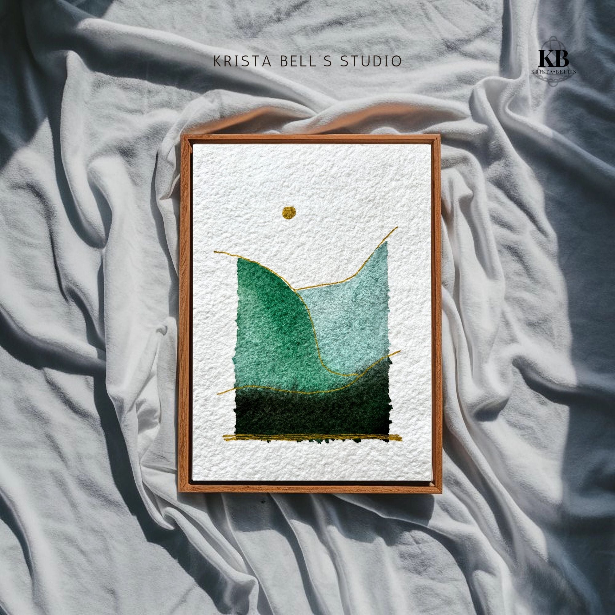 Framed artwork with green abstract design on textured fabric, featuring 'Krista Bell's Studio' branding.