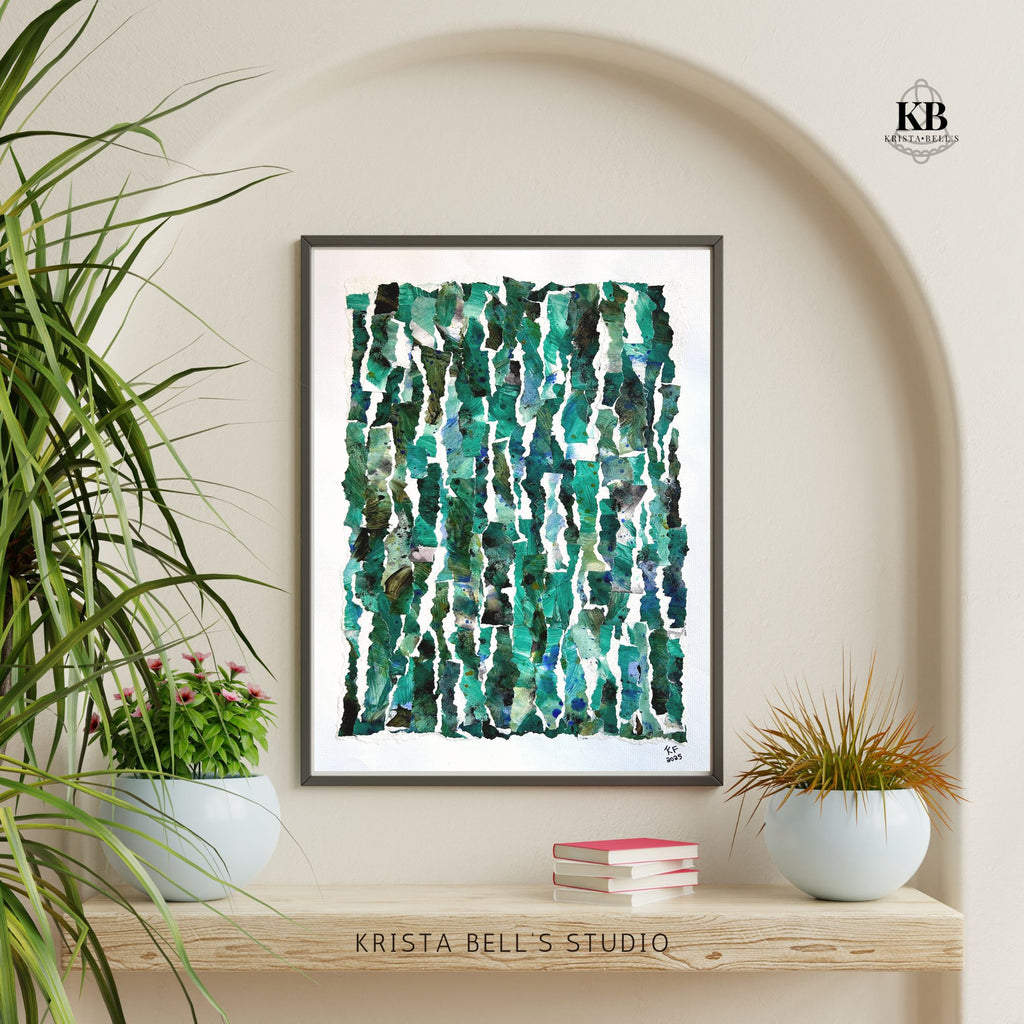 Framed abstract art print with green and blue patterns on a wall with plants and books below.