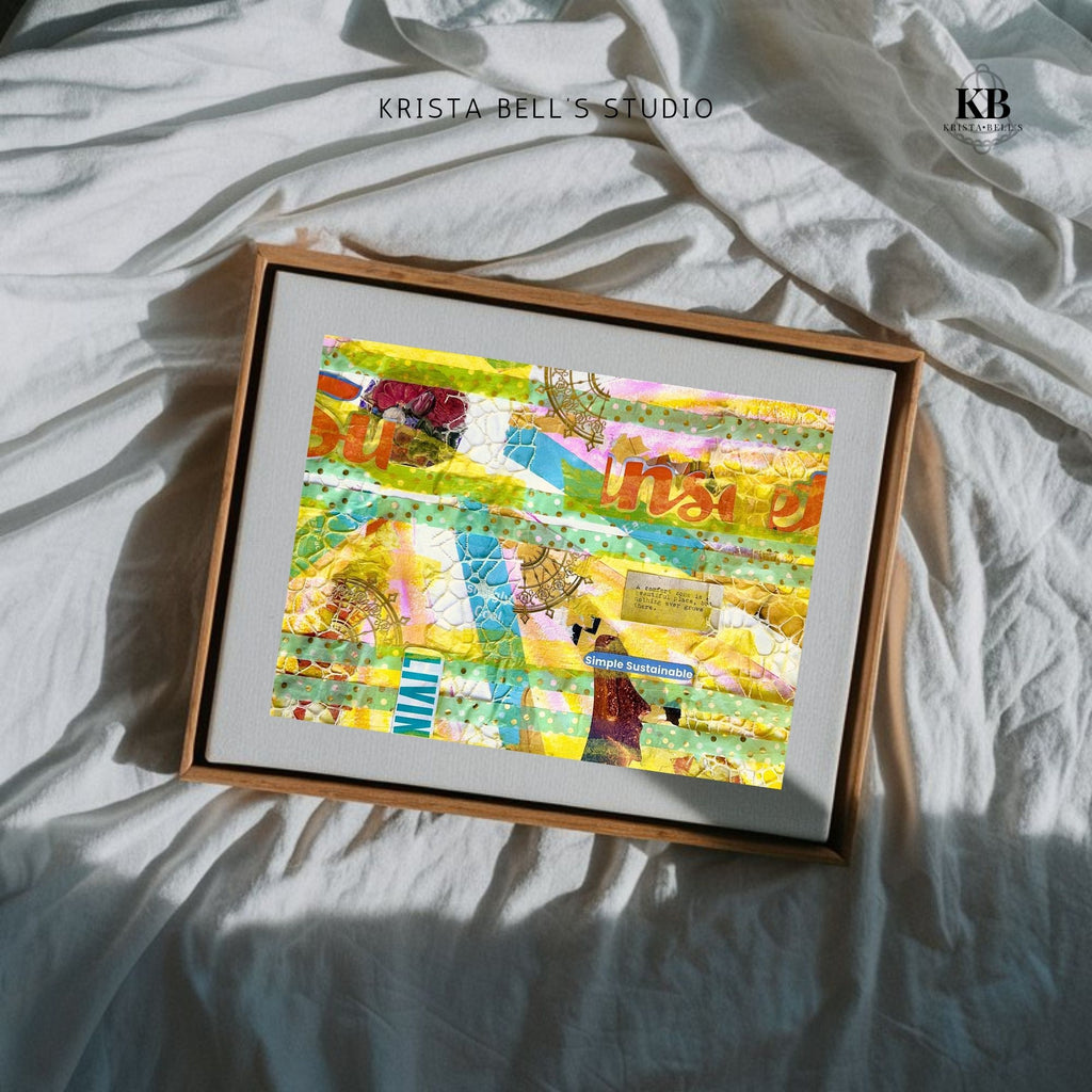 Framed colorful artwork on a light fabric background with 'Krista Bell's Studio' branding. A yellow and teal mixed media collage reflecting on the joy found in life when you thoughts, actions, and emotions align with your values. 