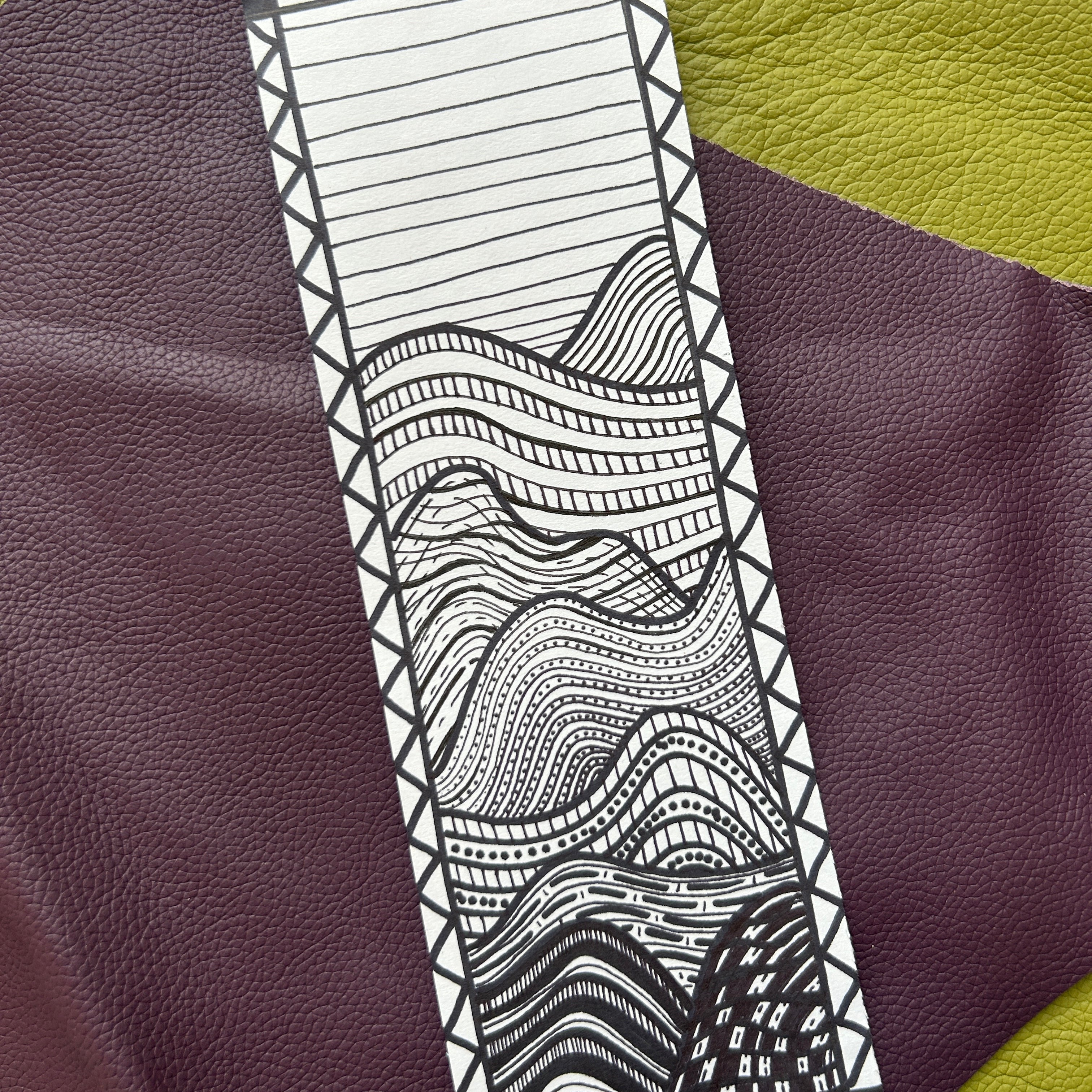 Black and white patterned strip on a textured purple and green fabric background