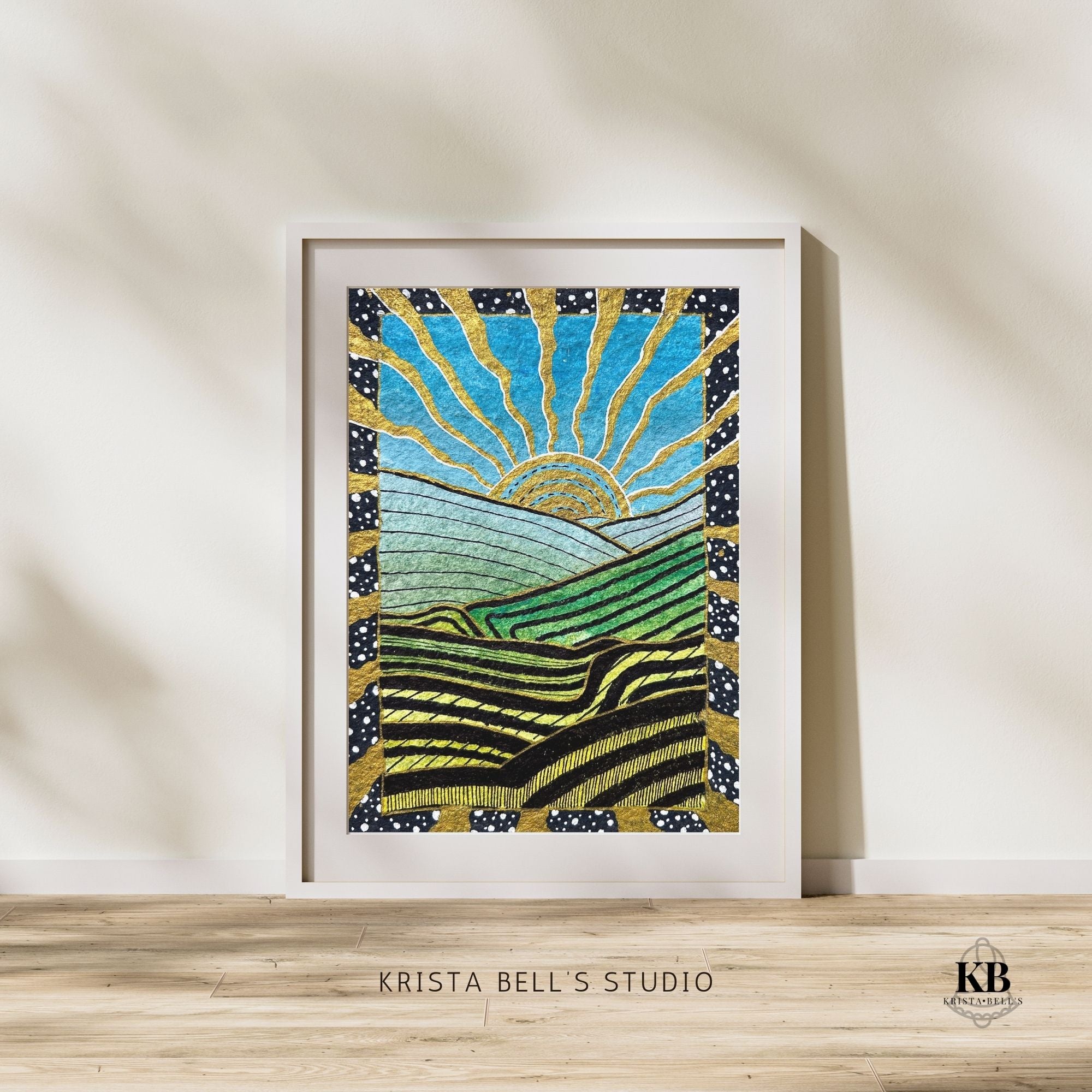 Framed artwork of a sun and landscape with 'Krista Bell's Studio' branding.