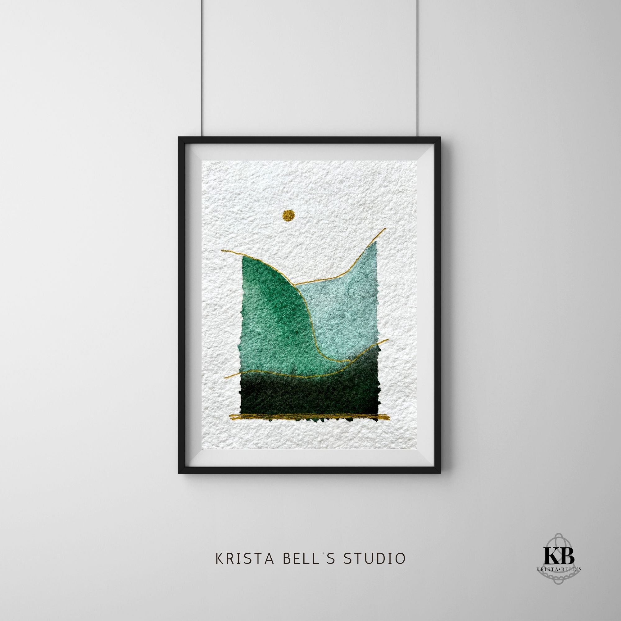 Framed simple modern watercolor landscape art piece with green and blue gradient on a white textured background with gold accents, hanging on a light gray wall.