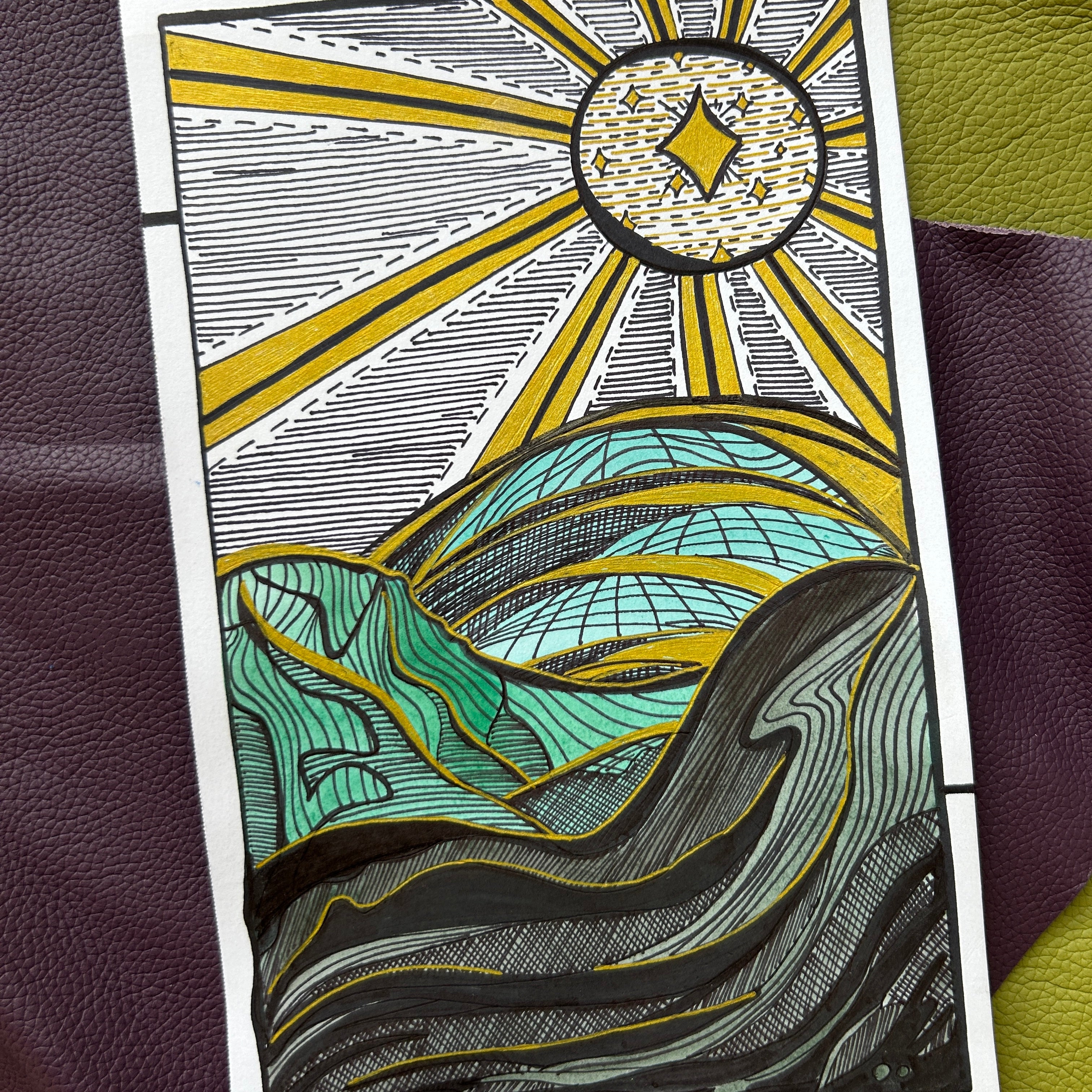 Decorative card with sun and mountain design on a textured surface