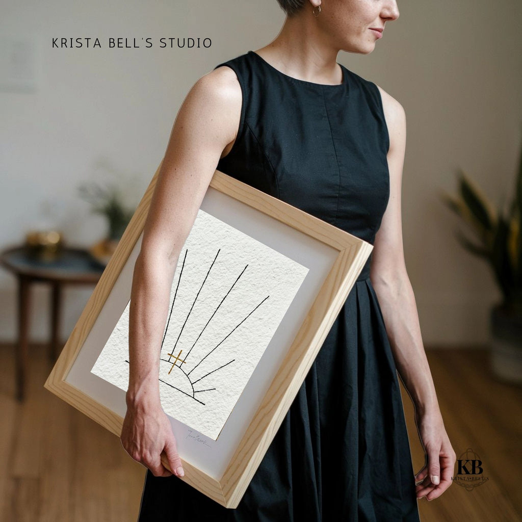 Person holding a framed piece of art with 'Krista Bell's Studio' branding.