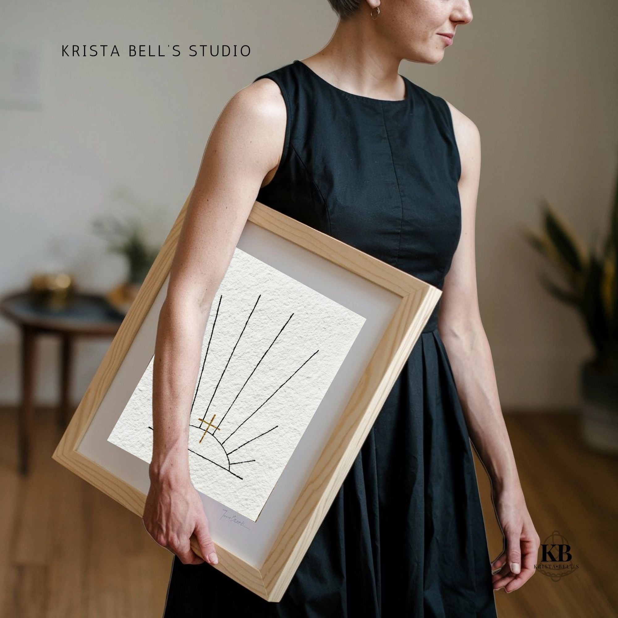 Person holding a framed piece of art with 'Krista Bell's Studio' branding.