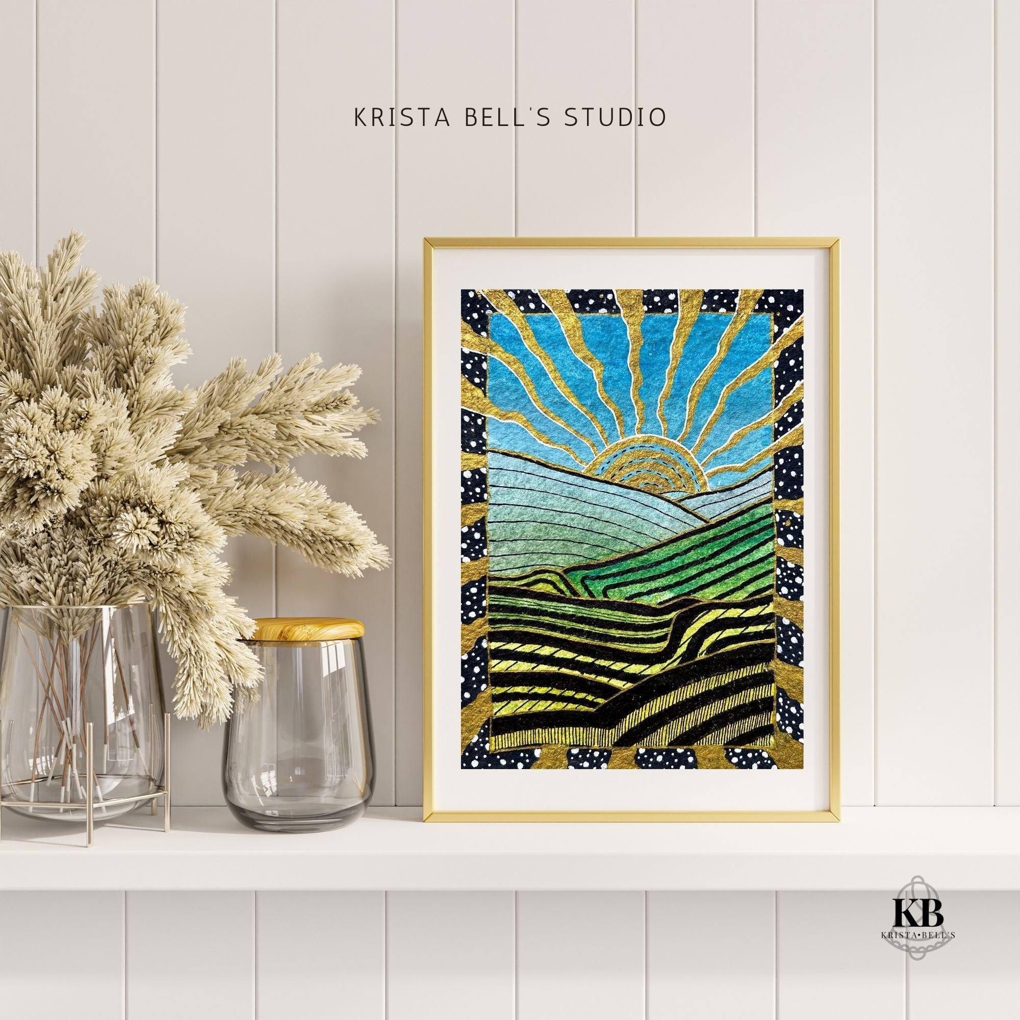 Framed artwork of a sun over fields with dried flowers and vases on a white surface, featuring 'Krista Bell's Studio' branding.