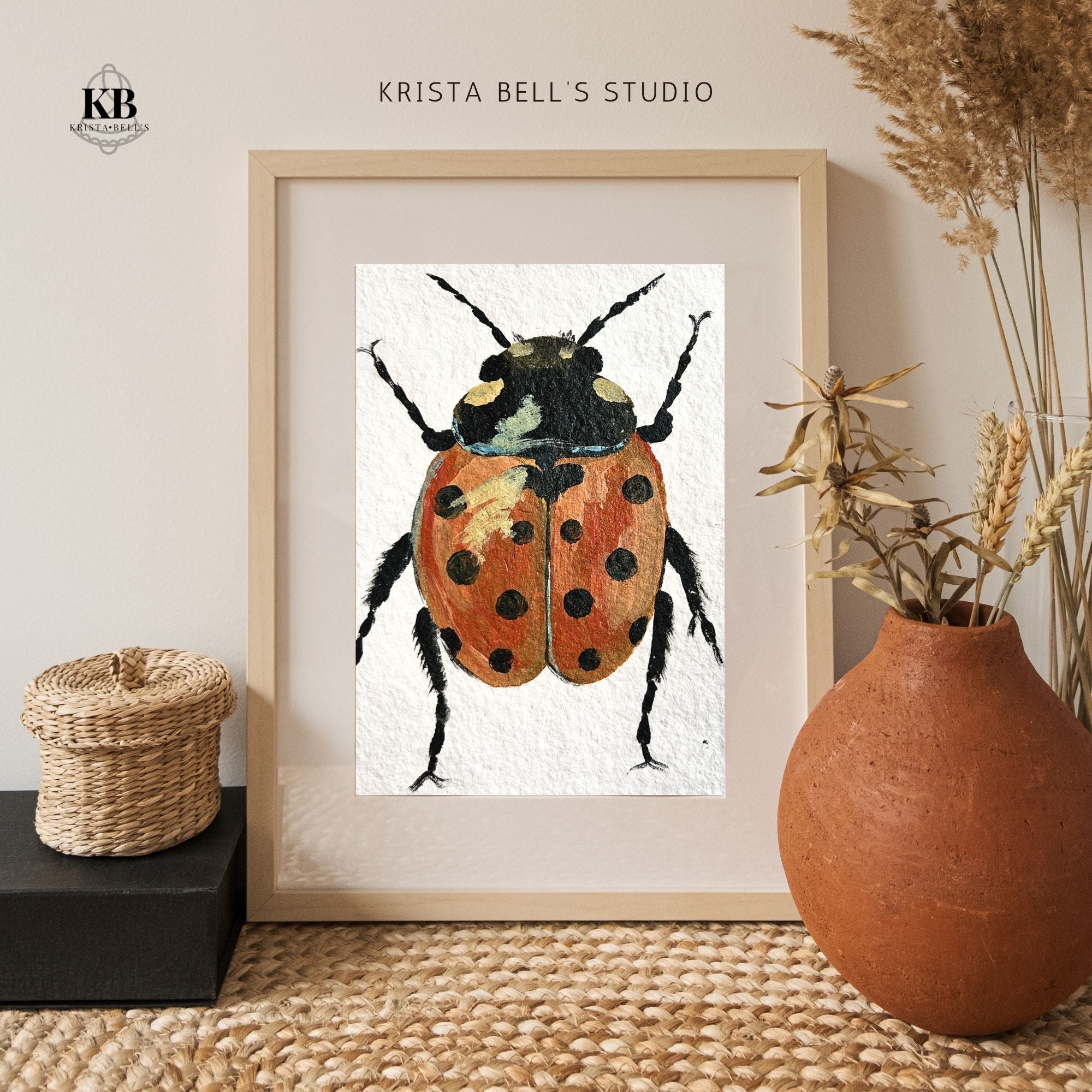 Framed artwork of a strong steady ladybug by Krista Bell's Studio on a neutral background with decorative elements.