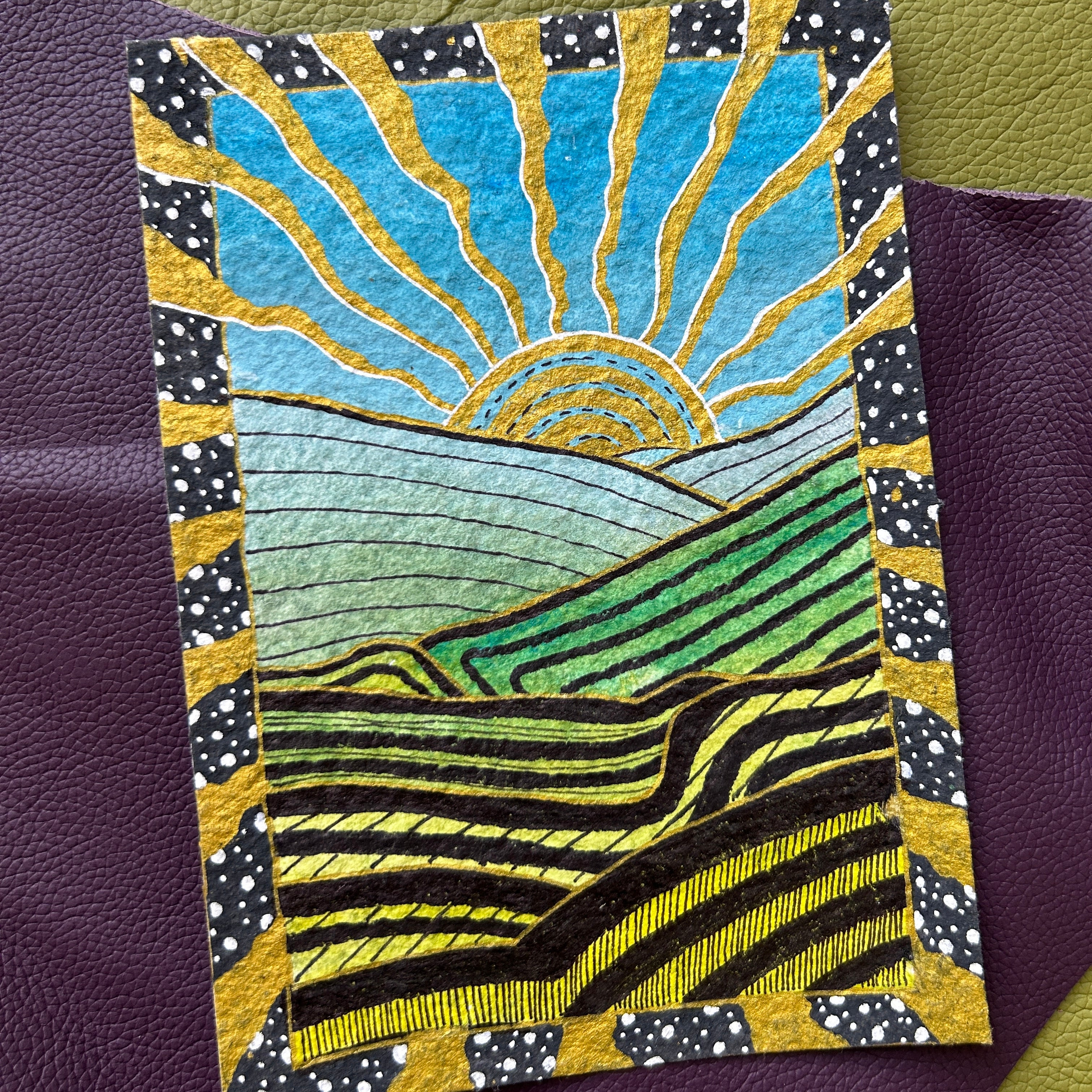 Decorative card with a sun and landscape design on a textured surface