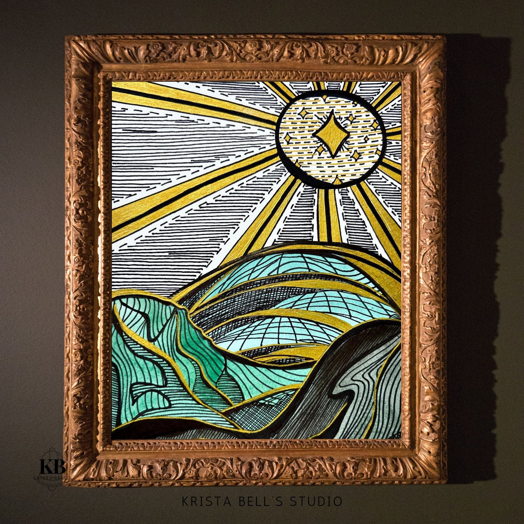 Decorative framed artwork with a stylized sun and hills design, featuring the artist's name 'Krista Bell's Studio'.