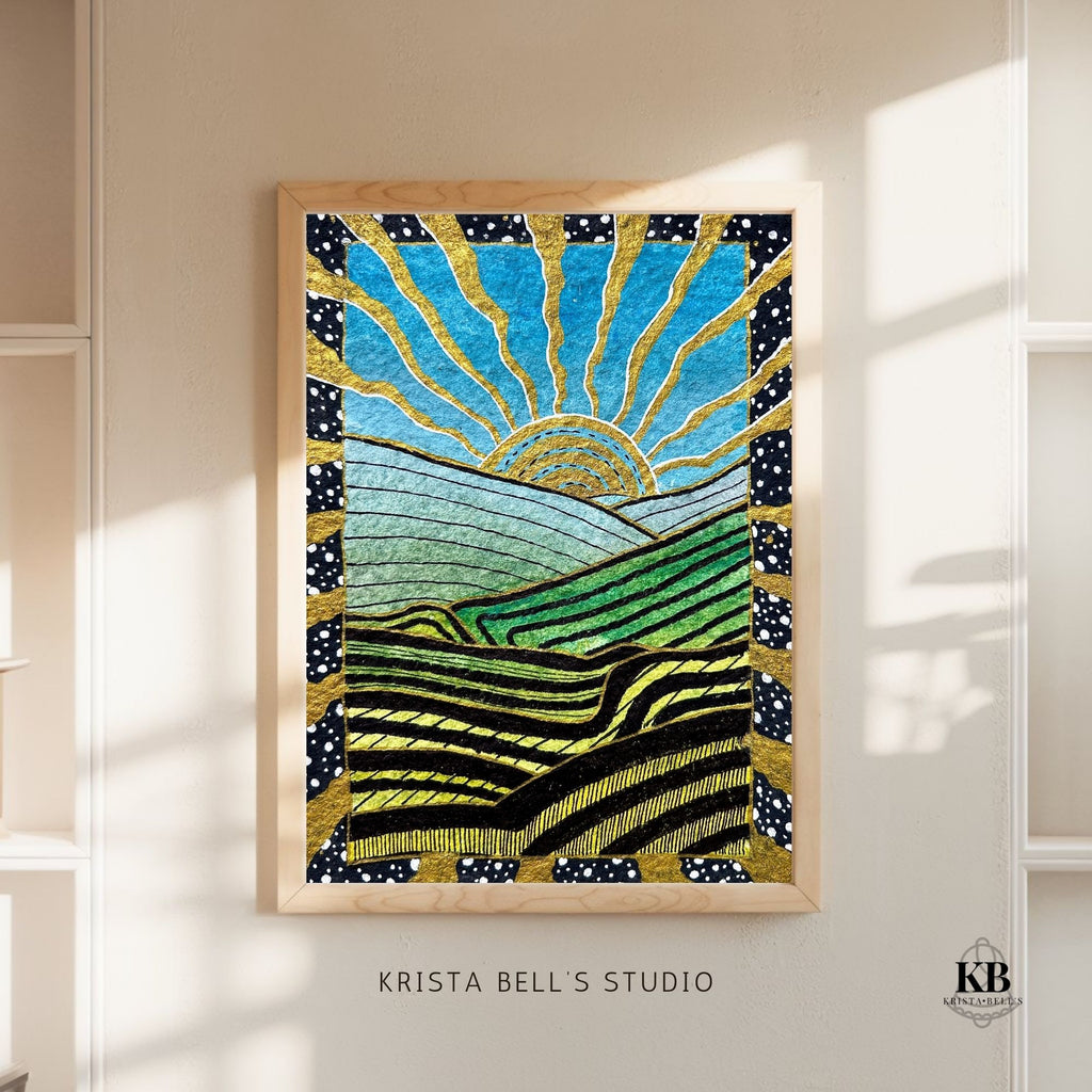 Framed artwork with a sun and landscape design on a wall, featuring 'Krista Bell's Studio' branding.