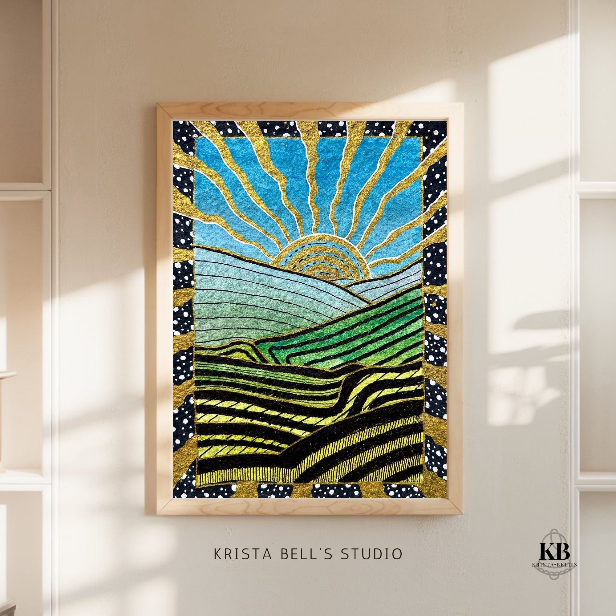 Framed artwork with a sun and landscape design on a wall, featuring 'Krista Bell's Studio' branding.