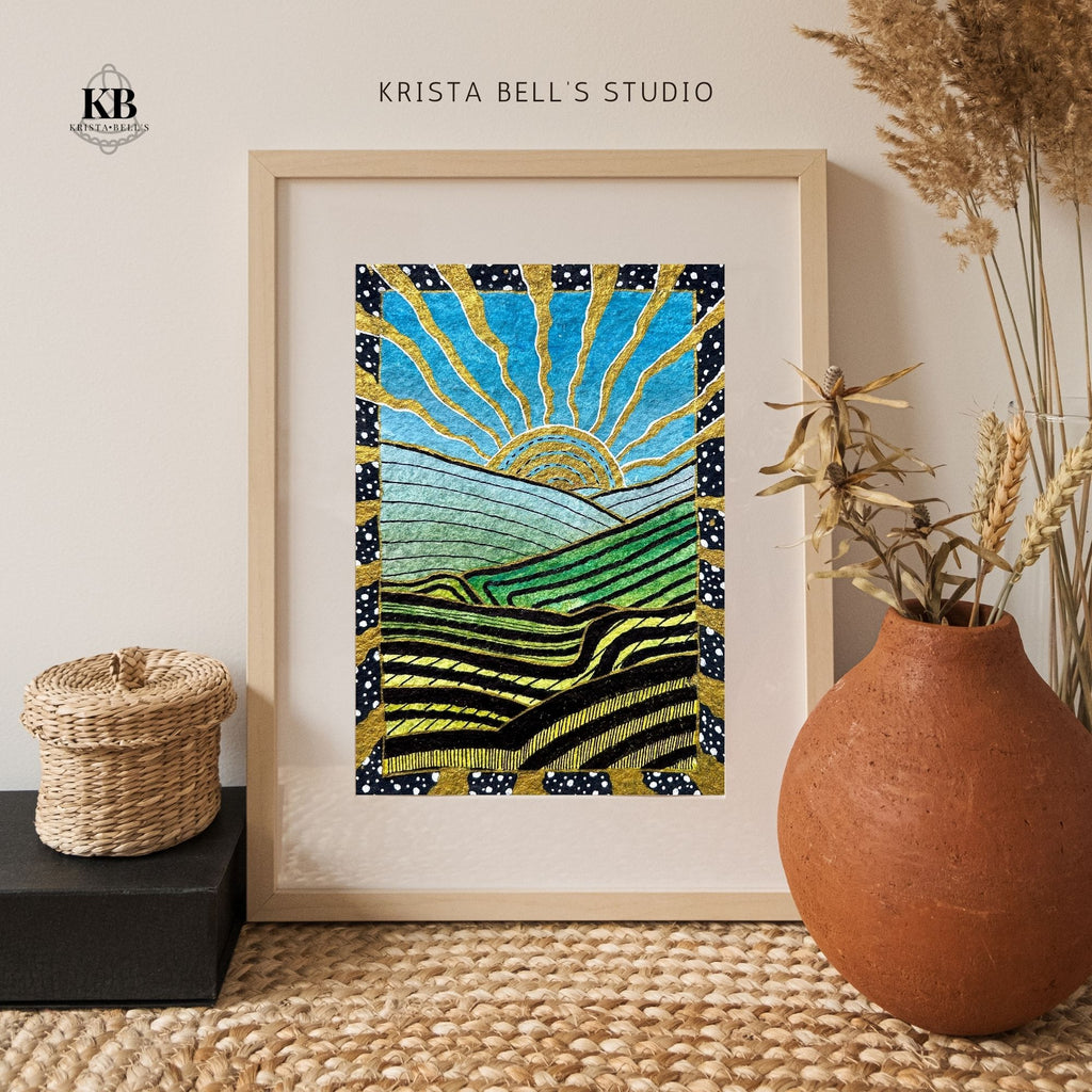 Framed artwork with abstract design of a sun and mountains, placed on a textured surface with decorative elements.