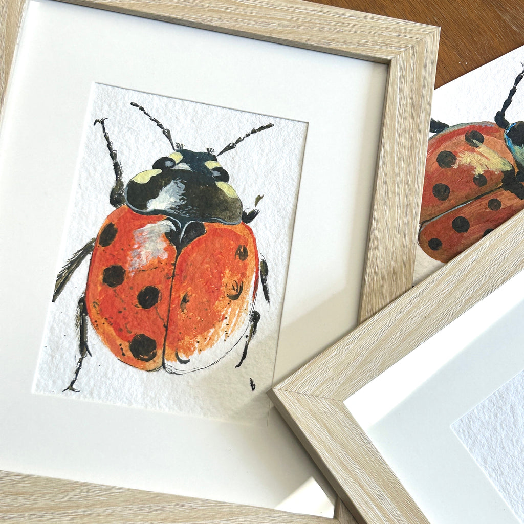 Framed artwork of a ladybug on a textured surface