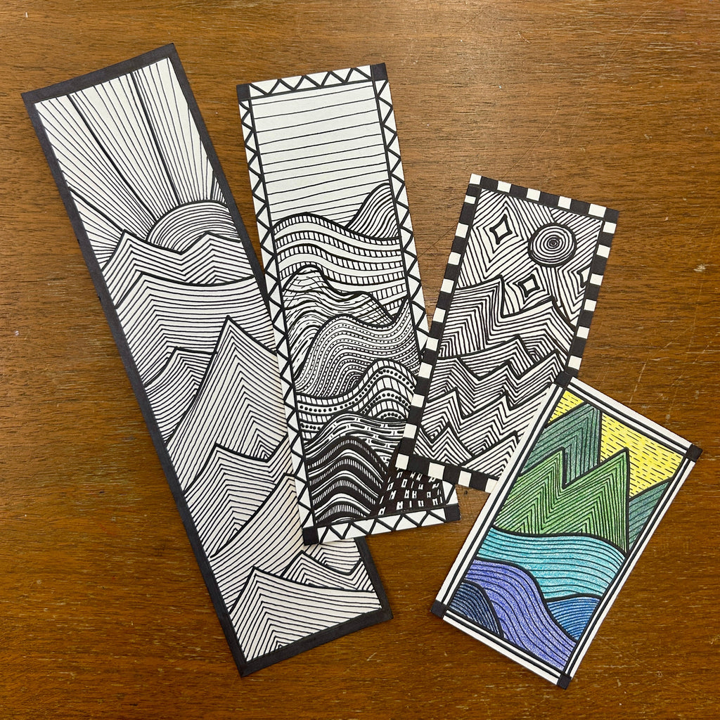 Four zentangle bookmarks on a wooden surface. Each depicting a modern geometric landscape ink drawing.