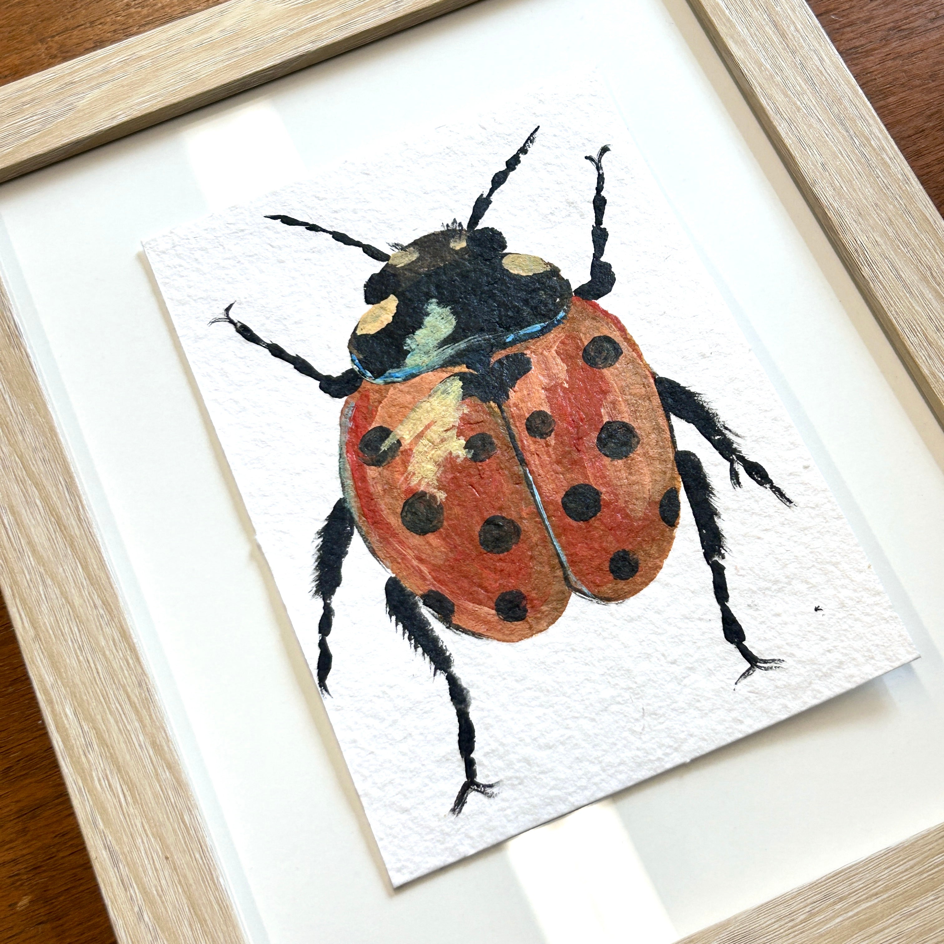 Framed artwork of a ladybug on a white background