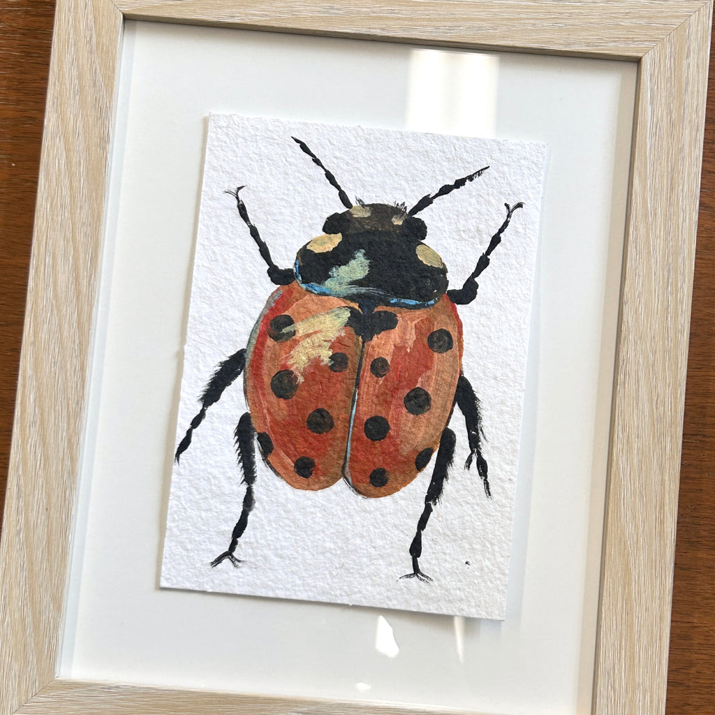 Framed artwork of a ladybug on a white background