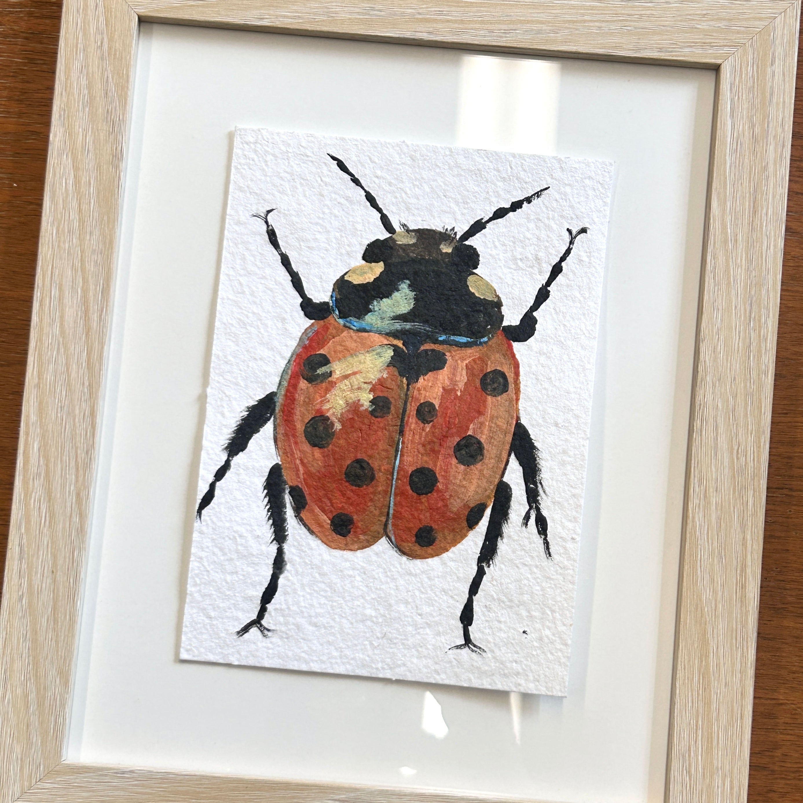 Framed artwork of a ladybug on a white background